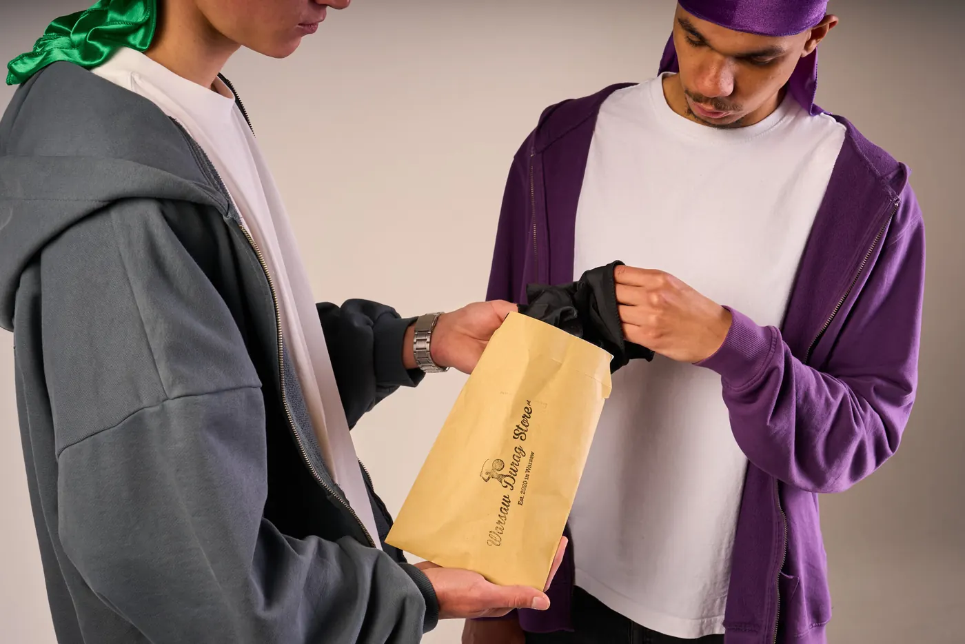 Dwóch modeli w duragach, jeden wręcza drugiemu kopertę Warsaw Durag Store